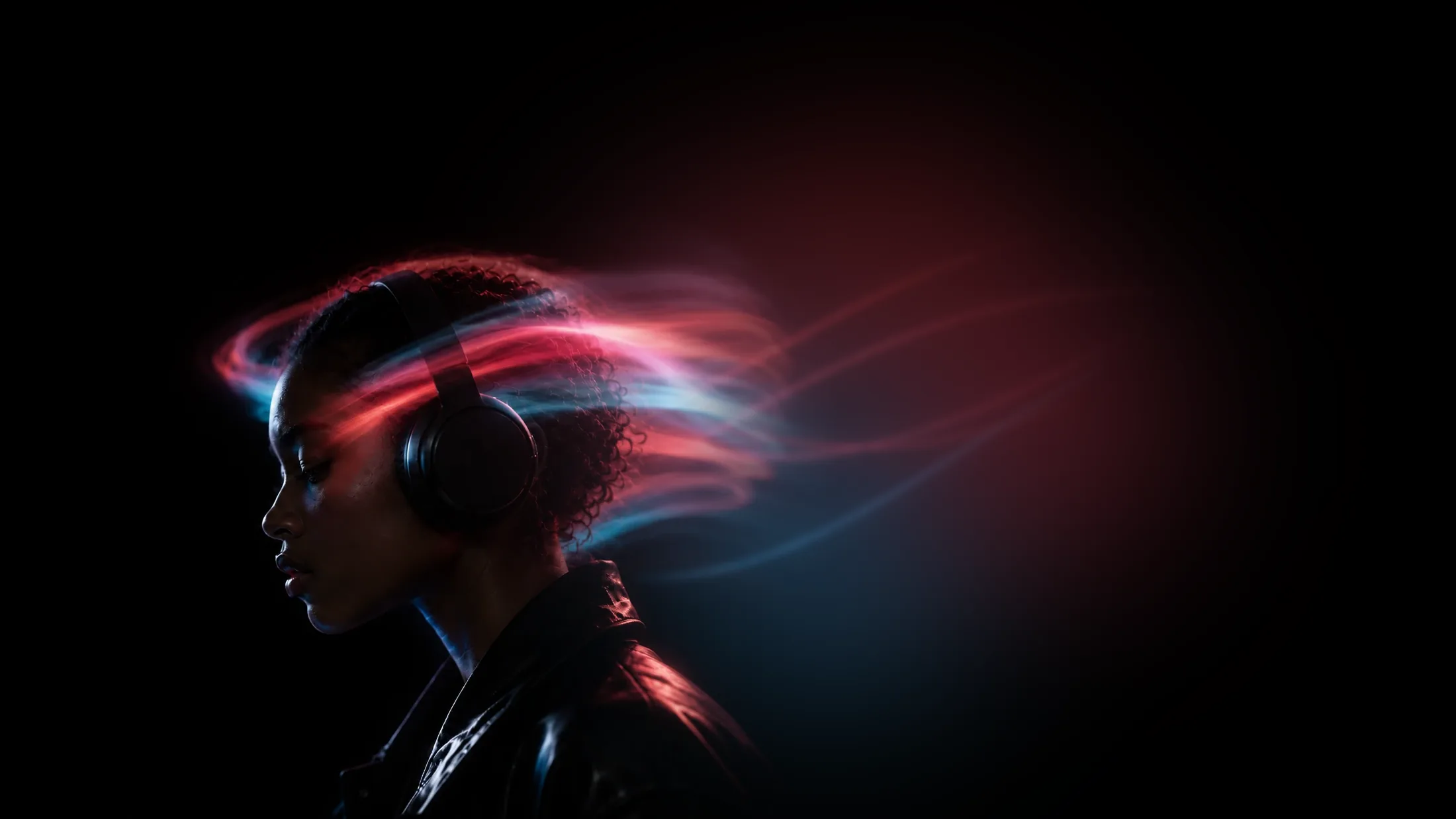 Profile of a woman with headphones in the dark, trails of red and blue light flowing from the back of her head